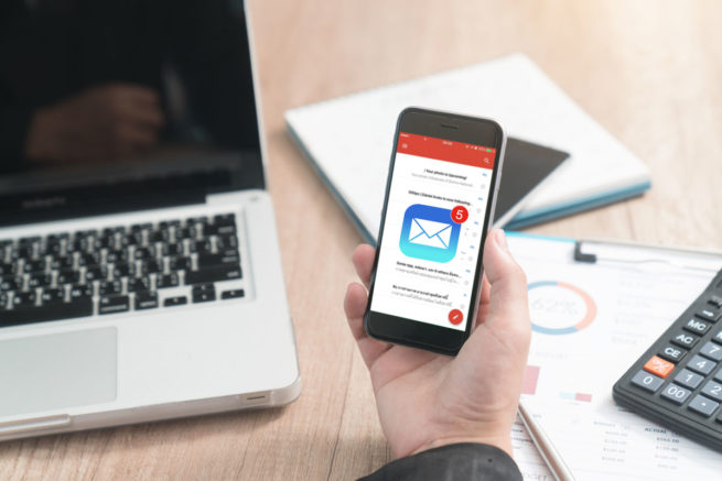 Une personne reçoit un nouveau message sur son téléphone et ouvre sa boite mail pour le lire.